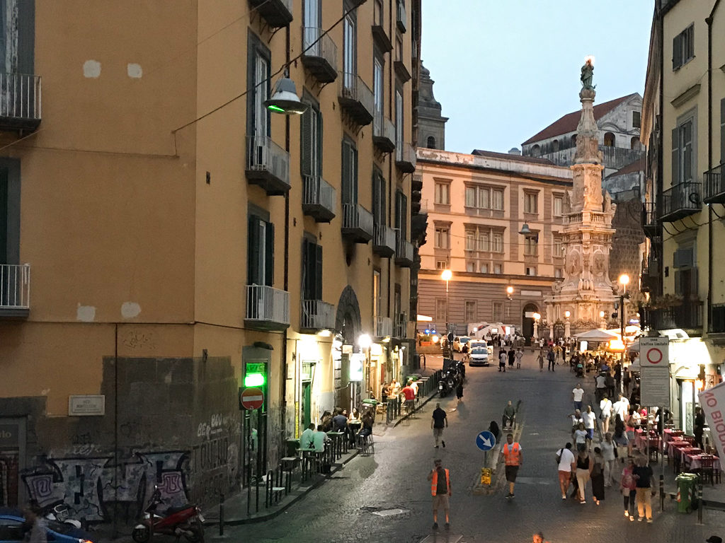 Sundown in street in Naples with statue in piazza 