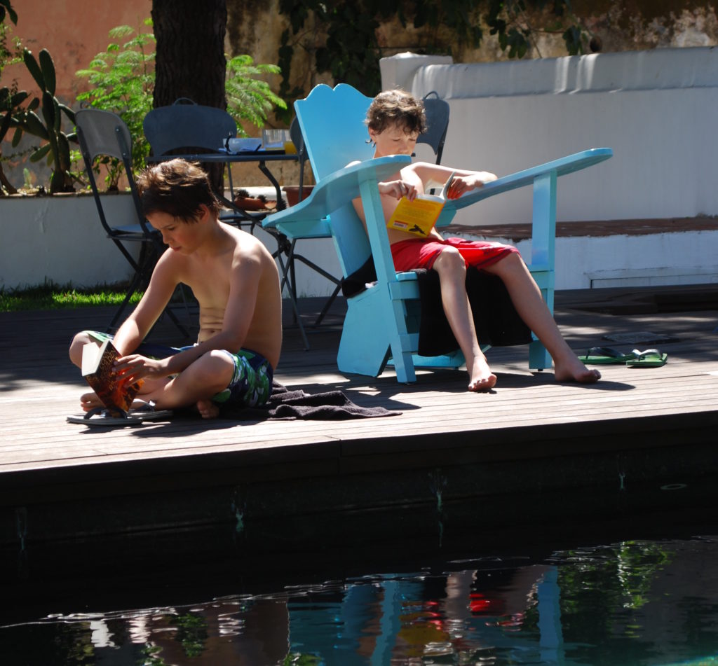 Family holidays in Lisbon. Reading by hotel pool, Palacio Belmonte. Copyright©2015 reserved to photographer. Contact mapandfamily.com