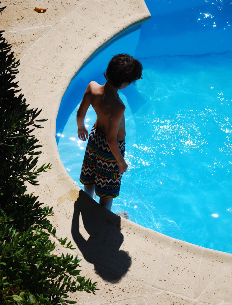 Boy standing at edge of swimming pool. Copyright©2015 reserved to photographer. Contact mapandfamily.com