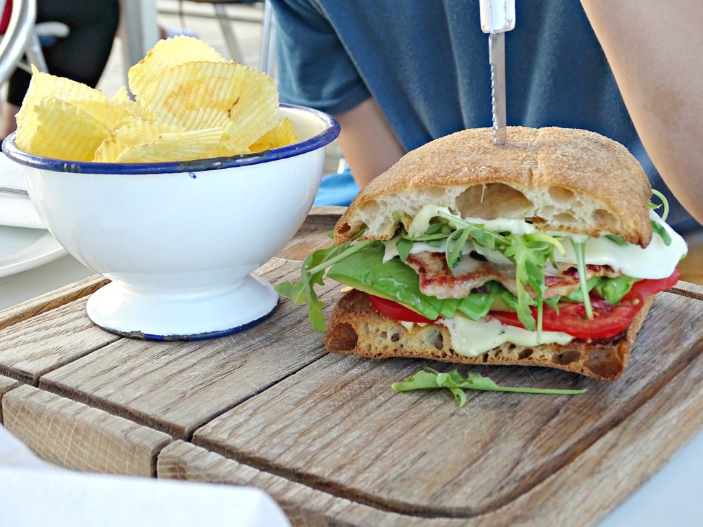 Club sandwich and crisps on an outdoor table at the beach. Copyright©2016 mapandfamily.com