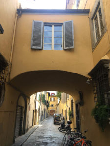 Street view in Oltrarno with ochre walls and an archway. Where to stay in Florence on a budget. Copyright©2018 mapandfamily.com