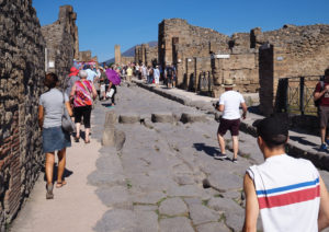 People walking along a cobbled street in Pompeii. Copyright©2019 mapandfamily.com
