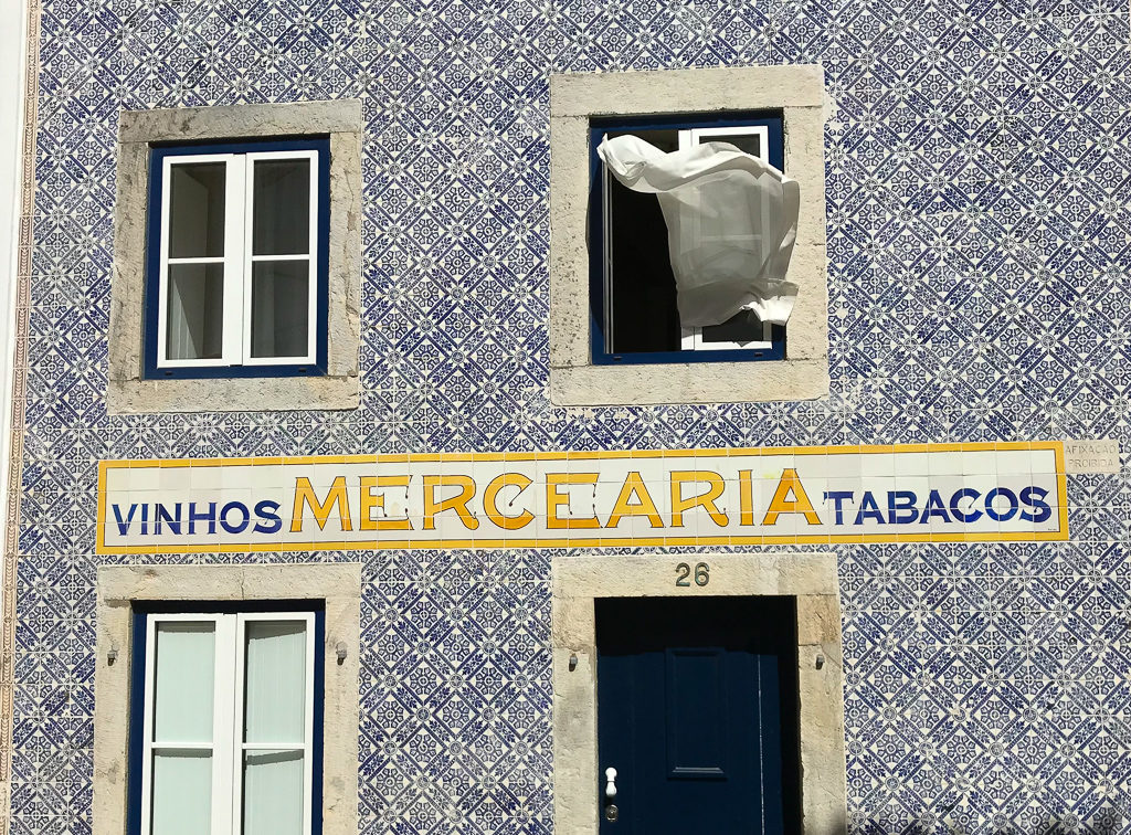 Tiled building in Cascais with white curtain blowing from window. Copyright ©2019 mapandfamily.com 