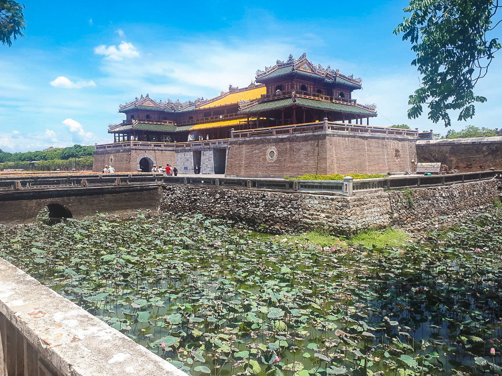 Vietnam highlights. Grand building in Hue surrounded by lilies on water. Copyright ©2019 mapandfamily.com 