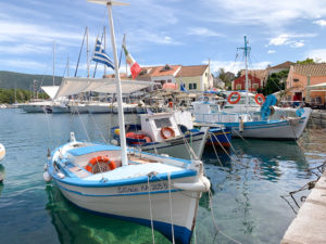 Small blue and white boats in Fiscardo harbour. Copyright ©2019 mapandfamily.com