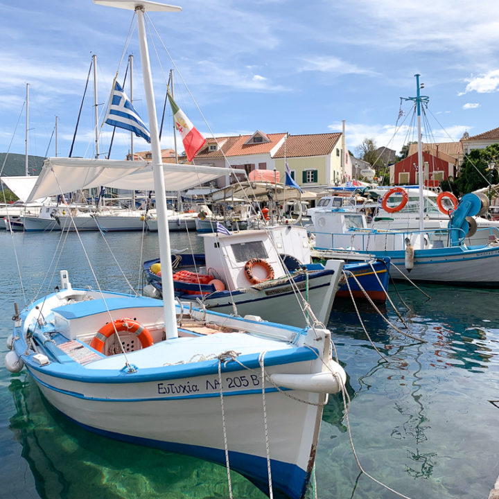 Small blue and white boats in Fiscardo harbour. Copyright ©2019 mapandfamily.com