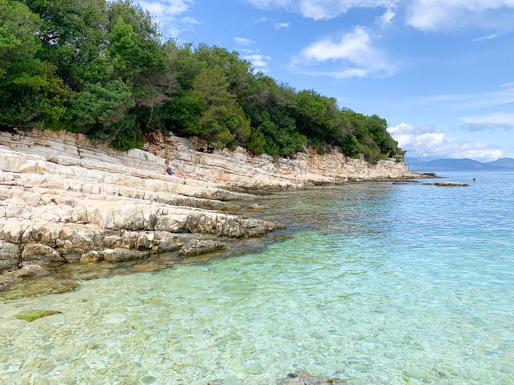 Kefalonia beaches. Sloping flat rocks beside clear turquoise water at Emblisi beach. Copyright ©2019 mapandfamily.com 