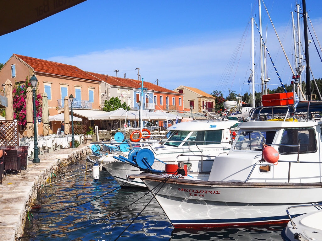 Things to do in Kefalonia. Fiscardo village waterfront with boats moored and coloured houses. Copyright ©2019 mapandfamily.com 