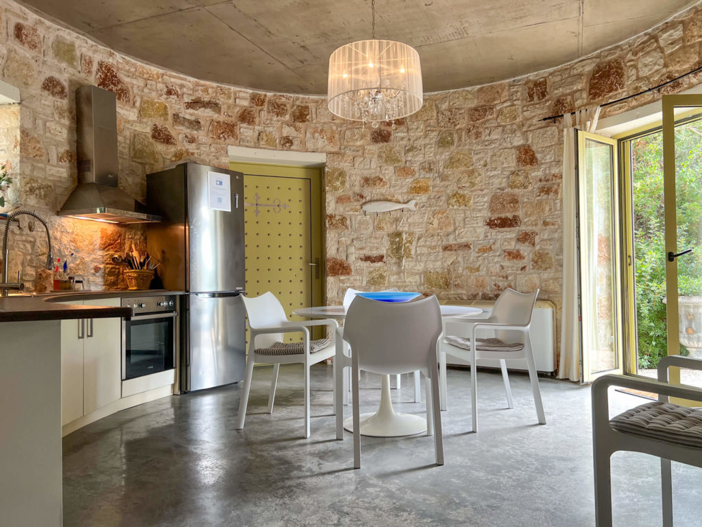 Circular kitchen in Thimari villa in Vasiliki Lefkada. Doors open to garden and table and chairs. Copyright@ 2022 mapandfamily.com 