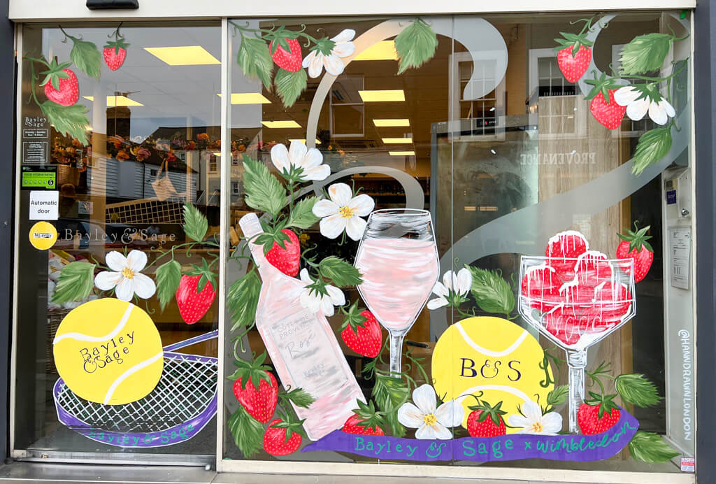 Shop window decorated with images of strawberries, rose wine and tennis balls. Copyright@2023mapandfamily.com 