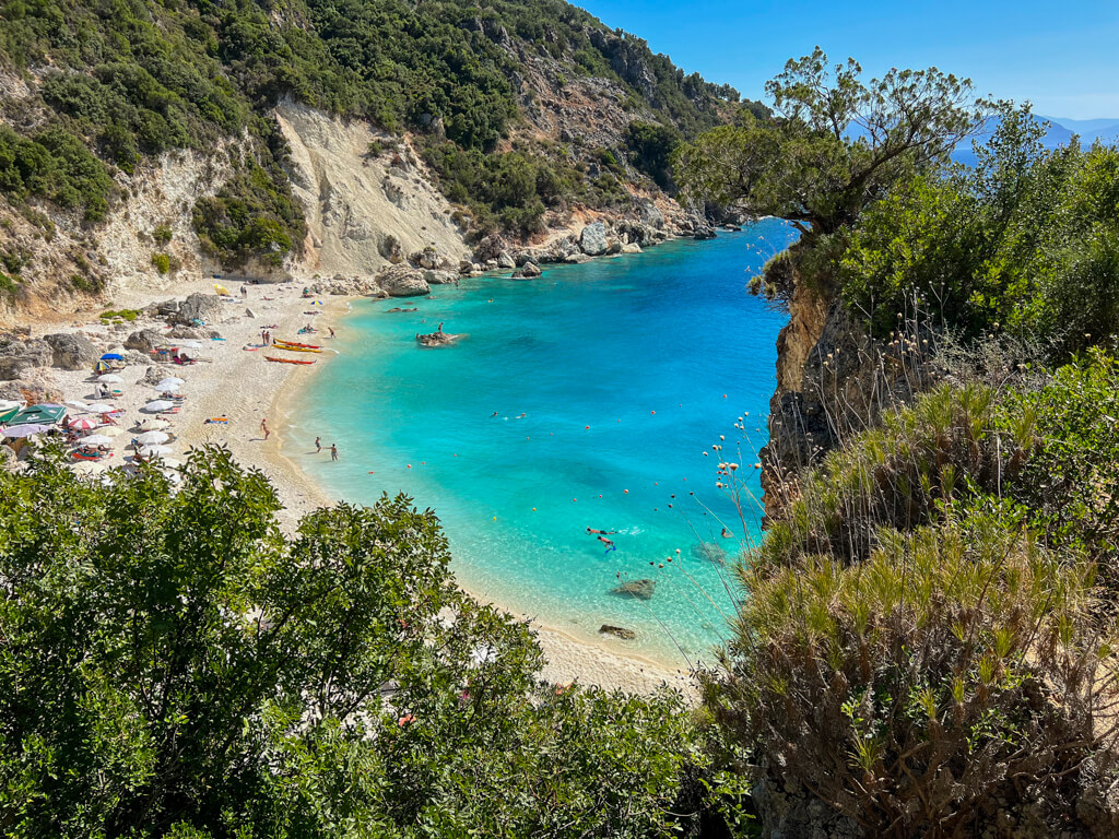 Clear calm turquoise sea at little cove with beach parasols at Agiofili beach Lefkada. Copyright@2023mapandfamily.com 
