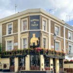 A historic pub called The Elephant and Castle with a golden sign depicting an elephant. Copyright@2023 mapandfamily.com