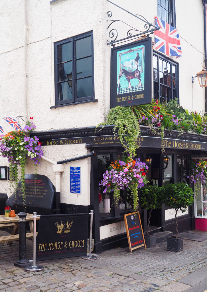 Exterior of pub with large colourful hanging baskets, union flat and painted sign. Copyright@2023 mapandfamily.com 