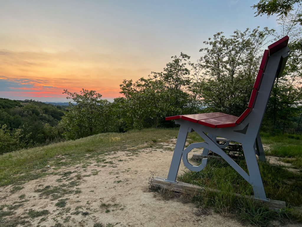 Piedmont region of Italy: sunset views from hilltop with oversized viewing bench in foreground. Copyright@2023 mapandfamily.com