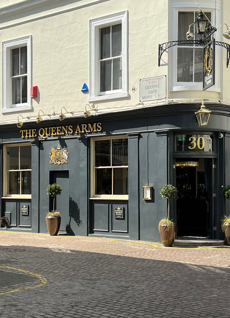 One of the best pubs near the Royal Albert Hall is The Queen's Arm painted black and cream with a gold sign. Copyright@2023 mapandfamily.com