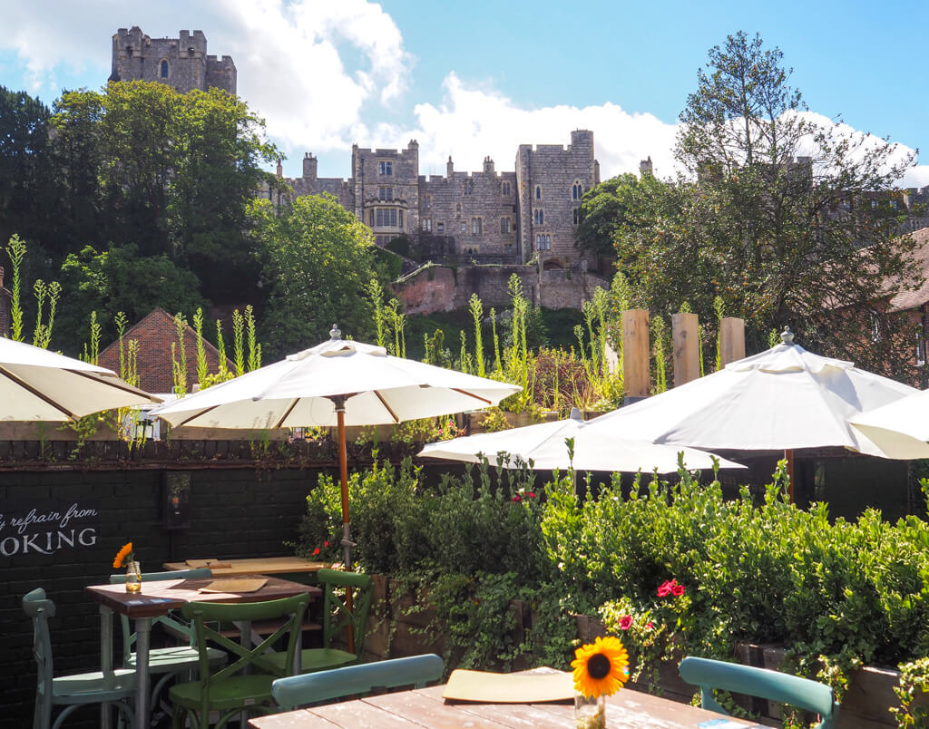 Old pubs in Windsor: garden with tables and chairs and parasols with Windsor Castle in the background. Copyright@2023 mapandfamily.com 