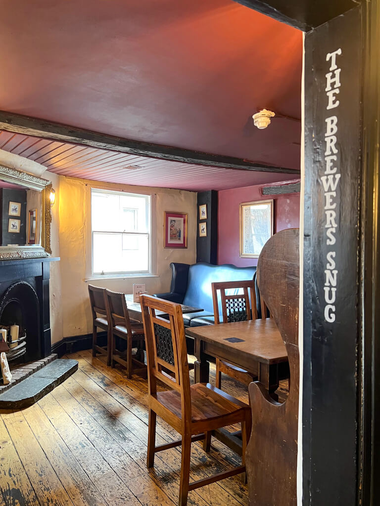 Interior snug with fireplace, settle and table and chairs at the George pub. Copyright@2023 mapandfamily.com 