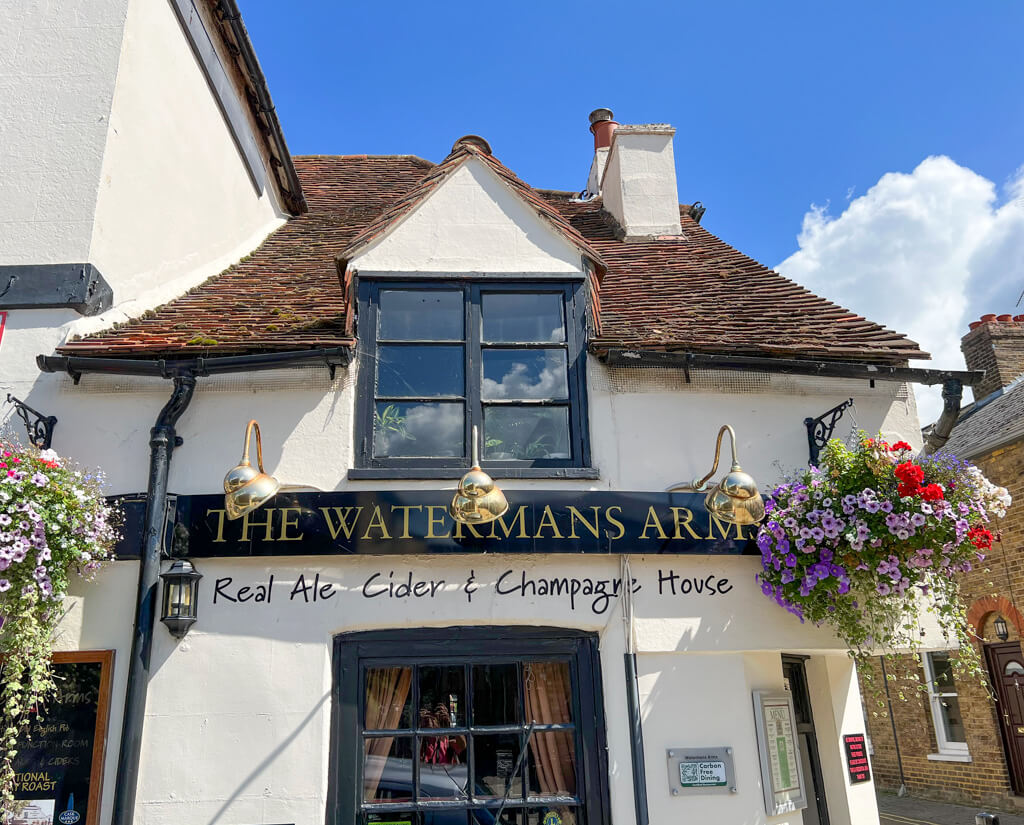 Black and white pub exterior at The Watermans Arms with lamps over its sign. Copyright@2023 mapandfamily.com 