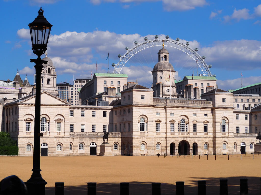 Historical places in London include Horse Guards Parade in foreground with London Eye in the background against blue sky. Copyright@2023mapandfamily.com 