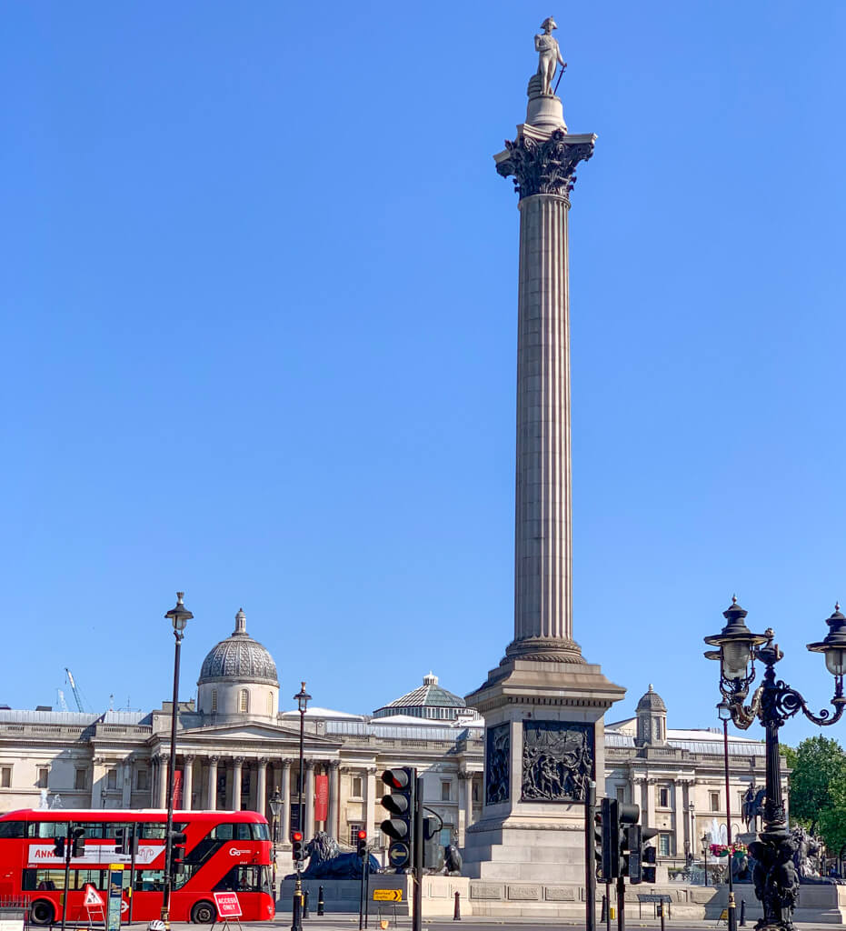 Nelson's Column standing tall against blue sky with National Gallery in background. Copyright@2023mapandfamily.com 