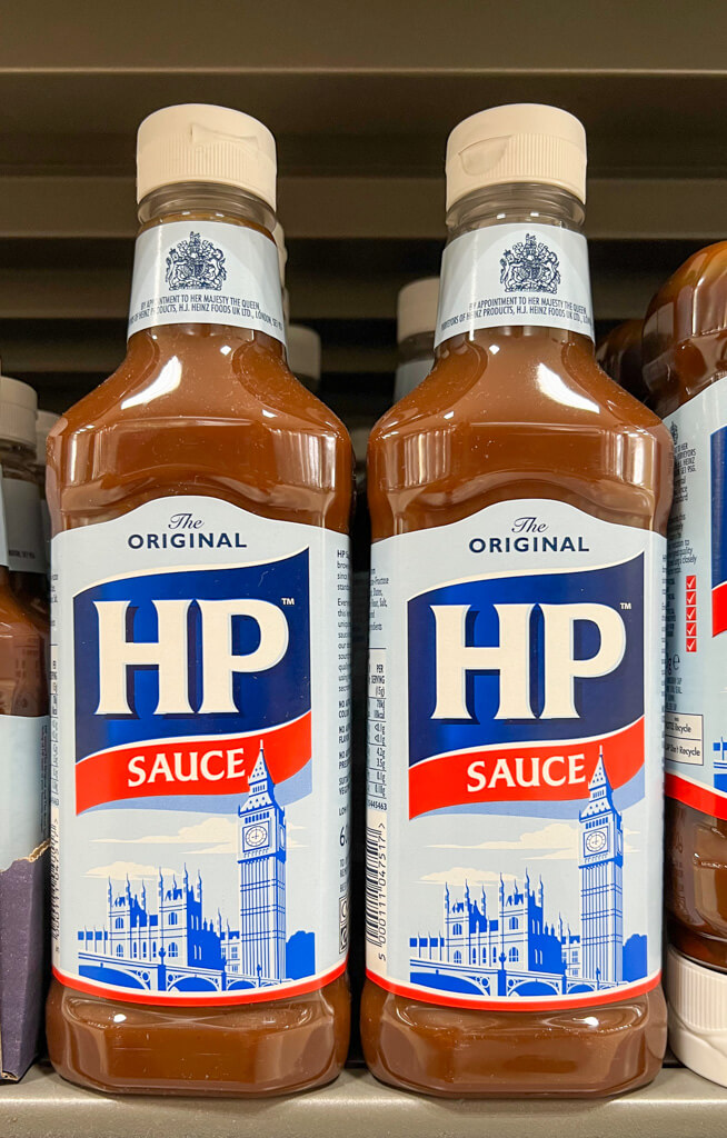 Two bottles of HP sauce on a shelf showing the illustration of Houses of Parliament on the label. Copyright@2023 mapandfamily.com 