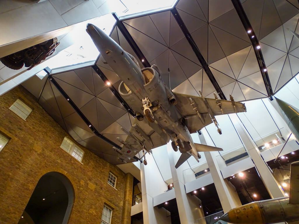 Looking up at a fighter plane suspended from the ceiling in the Imperial War Museum. Copyright@2023 mapandfamily.com