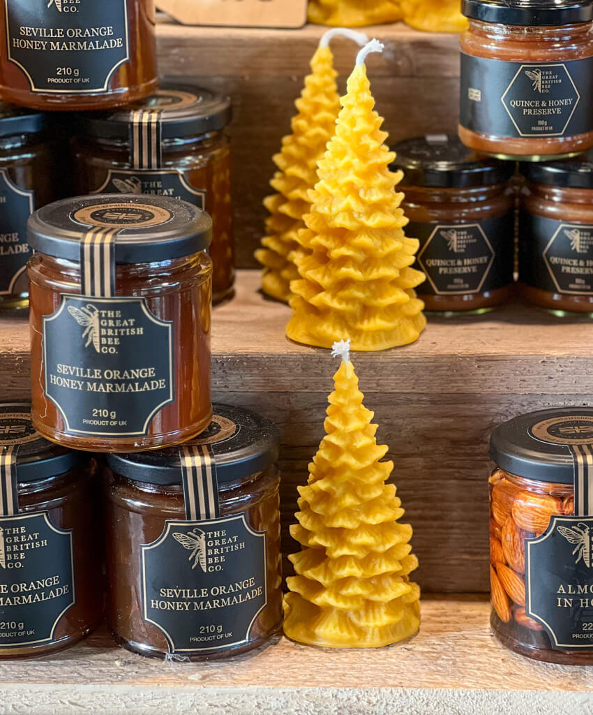 Beeswax candles in shape of fir trees and jars of honey marmalade on stalll. Copyright@2023 mapandfamily.com