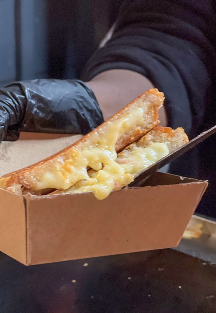 Cheese toasty in a takeawy tray at street food stall. Copyright@2023 mapandfamily.com