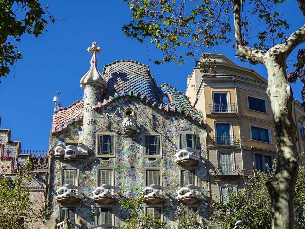 Gaudi's fantastical and colourful Casa Battlo against a bright blue sky in Barcelona. Copyright@2024 mapandfamily.com 