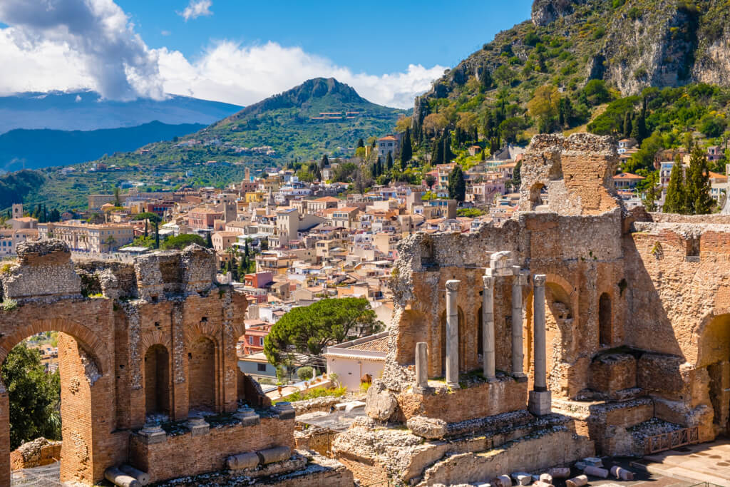 Greek ruins in Taormina in Sicily overlooking the bay and Mount Etna volcano. 