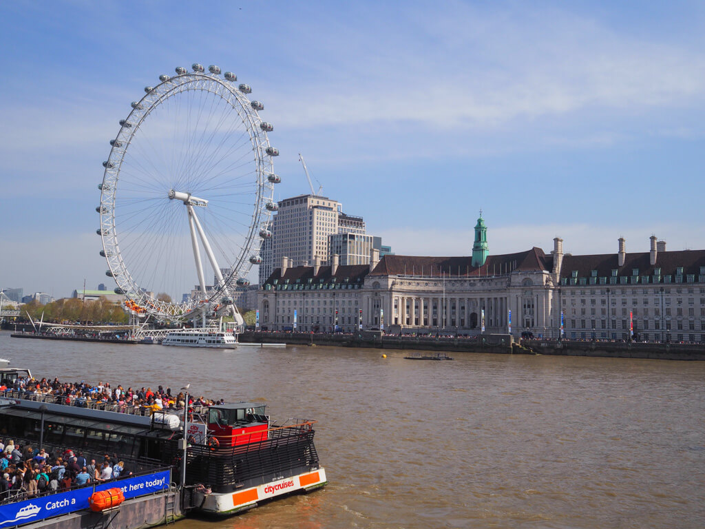 A fine day in London in April with view of London Eye and Thames cruise boat full of sightseers on open top. Copyright@2024mapandfamily.com 