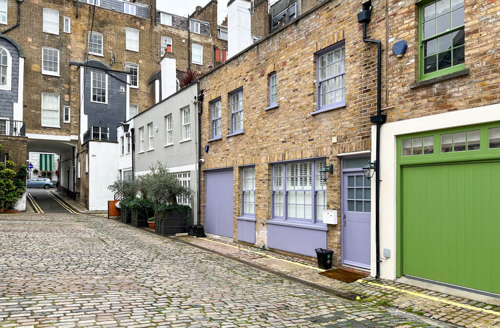 A colourful mews in Paddington with cobblestones and brightly painted doors. Copyright 2024@mapandfamily.com 