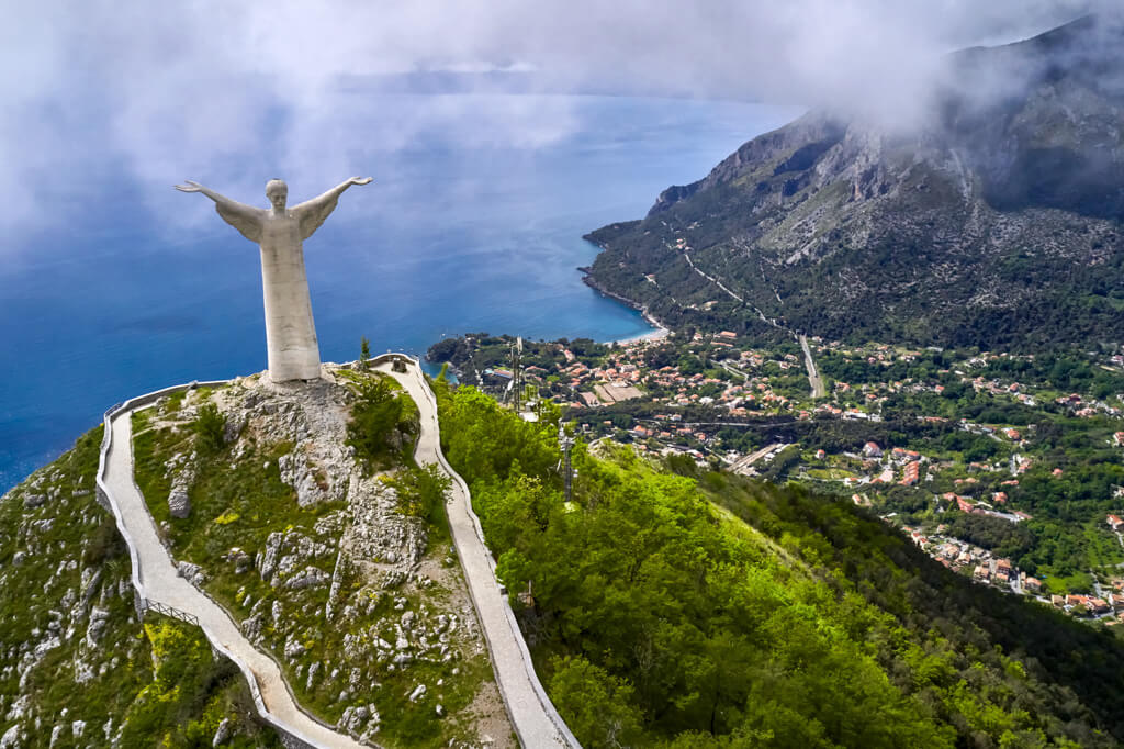 Maratea Italy, bird's eye view of statue of Christ the Redeemer with arms outstretched high above the town and mountainous coastline. copyright/Depositphotos.com 