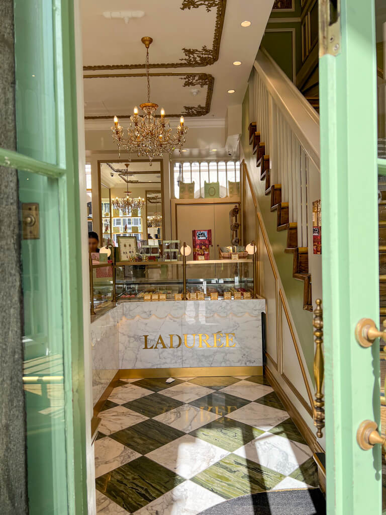 Through a green doorway looking into Laduree cafe in Covent Garden. Copyright@2024mapandfamily.com 