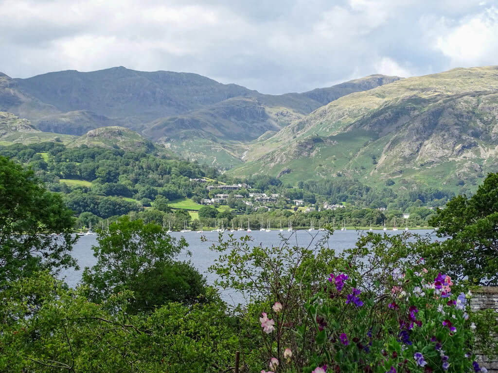 Typical England countryside landscape of Lake District lake and boats with green slopes of hills in background. Copyright@2025NancyRoberts