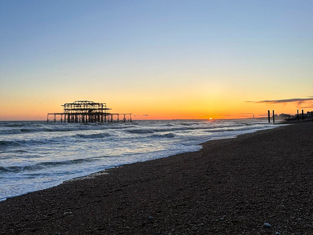 The remaining framework of the derelict West Pier off the shore at Brighton, silhouetted against the sunset. Copyright@2024 mapandfamily.com 