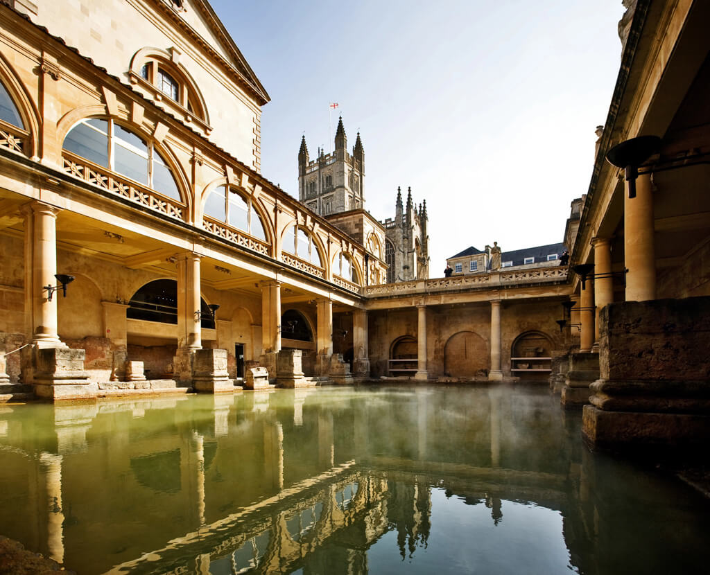 One of the most historic nearby cities to London is Bath. Image shows its Roman thermal baths with a pool surrounded by colonnades. 