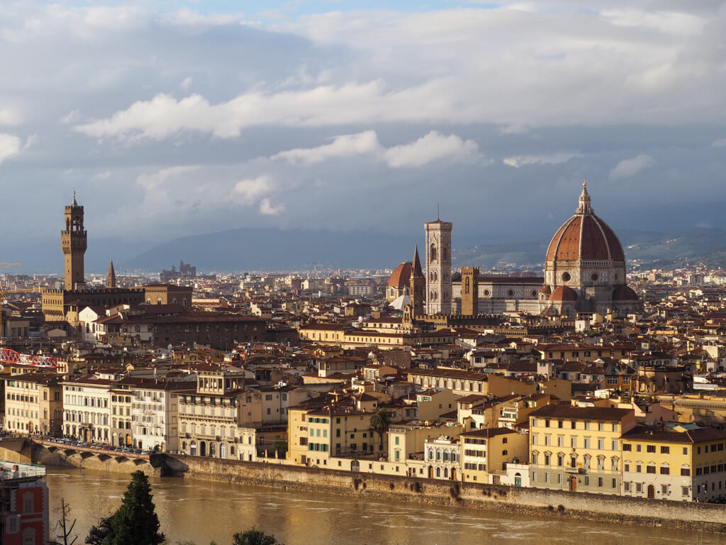 Florence's skyline with dome and towers, overlooking the river Arno, against a grey cloudy sky. Copyright@2024 mapandfamily.com 