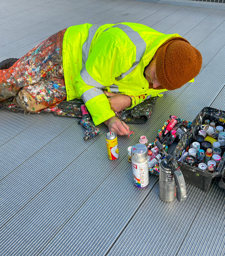A fun thing to do in London with teens is to spot the chewing gum art on Millennium bridge. Here is artist Ben Wilson painting tiny works of art on the treads of the bridge. Copyright@2024 mapandfamily.com 