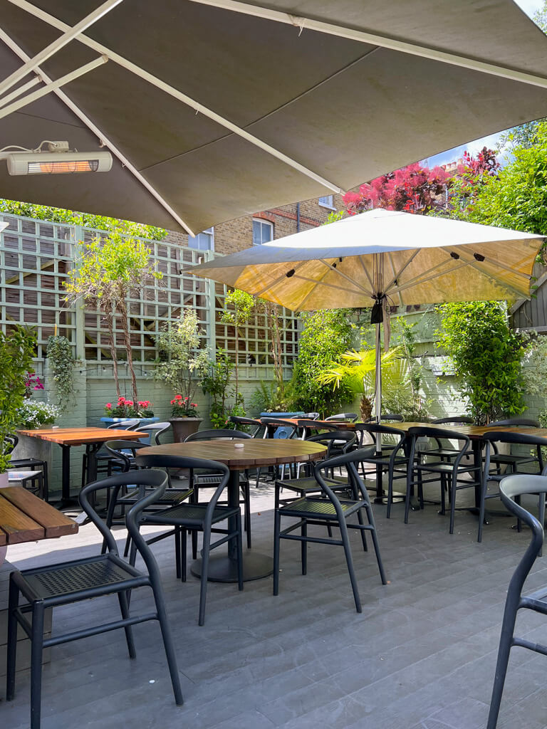 Secluded patio with tables and umbrellas at Patara Thai restaurant in Wimbledon. Copyright@2024 Nancy Roberts