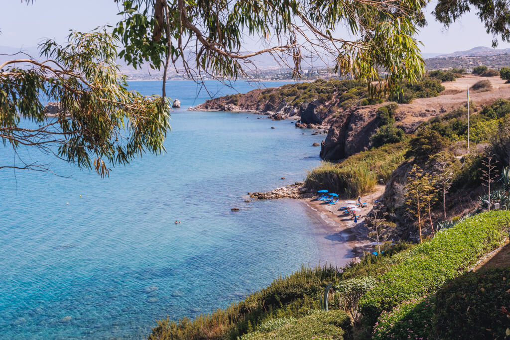 The ragged rocky coastline of the Akamas penisula showing a small beach with parasols. 