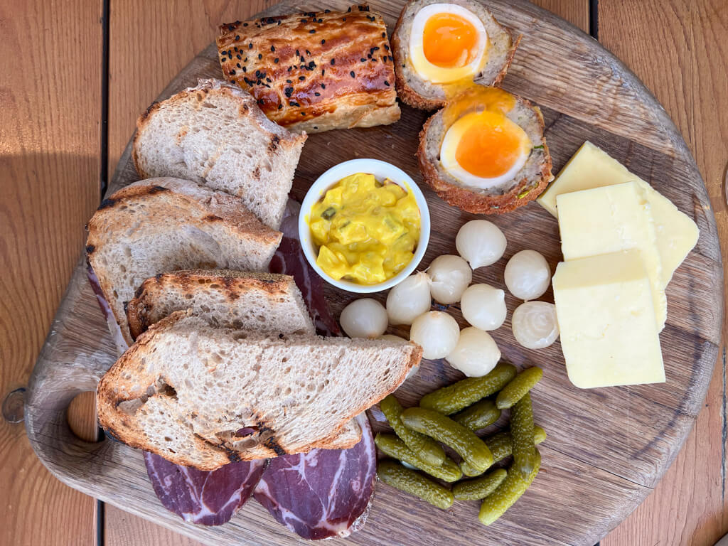 A ploughman's lunch served in a London pub on a wooden platter. Copyright@2024NancyRoberts