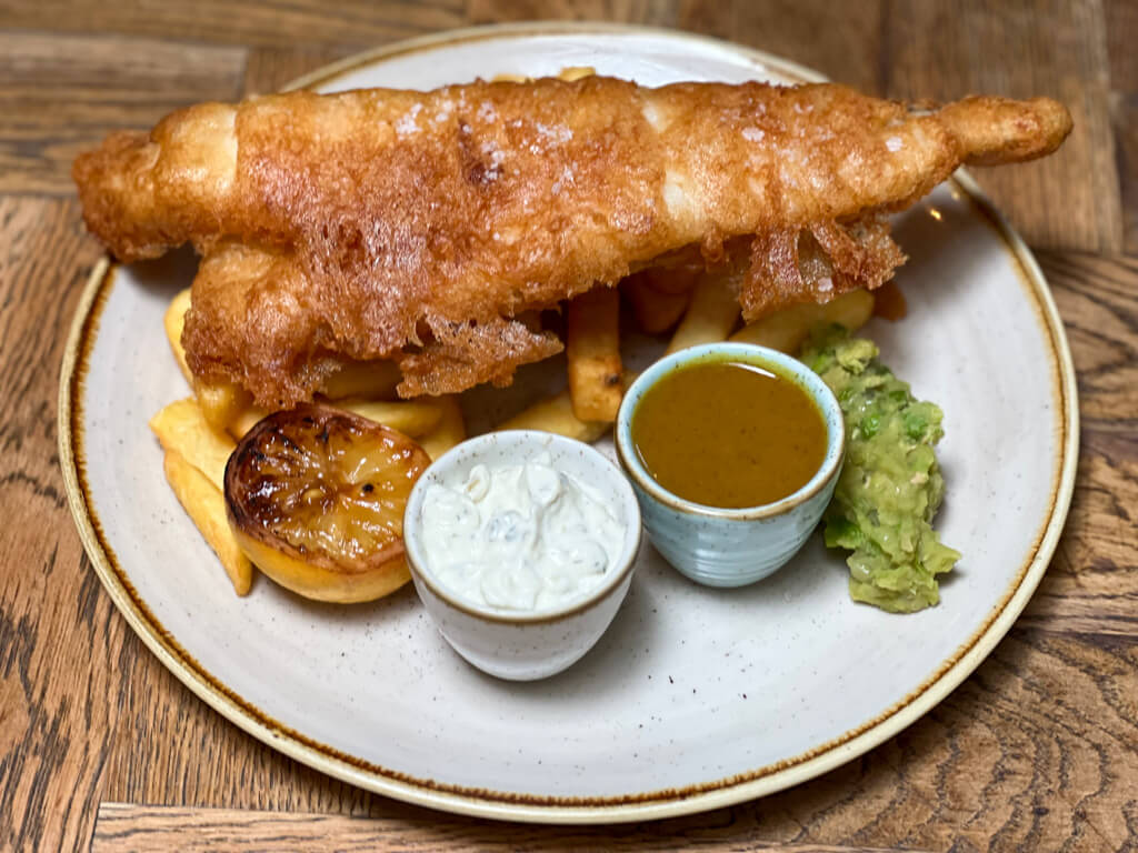 London food: a pub serving of battered fish with chips, mushy peas and pots of tartare sauce and gravy.Copyright@2024NancyRoberts