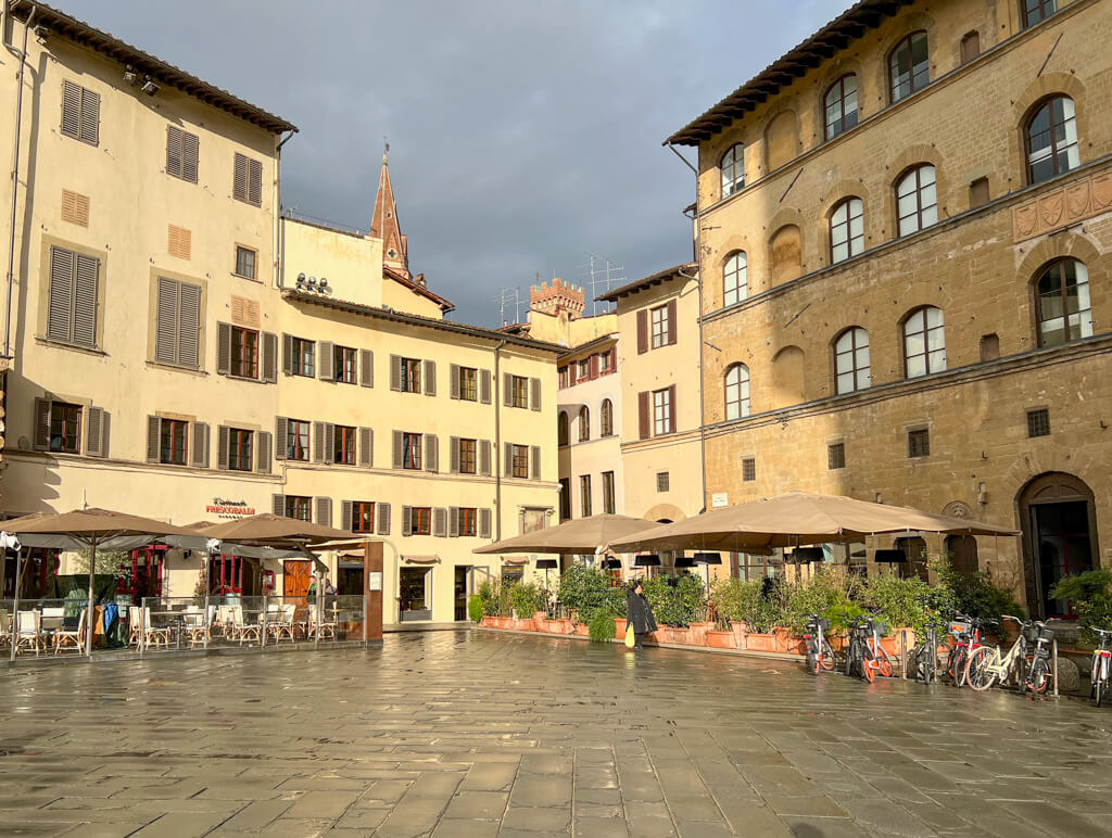 A quiet corner in Piazza della Signoria in Florence, Italy. Tall historic buildings are painted in pale shades of yellow and ochre. Copyright@2024 NancyRoberts