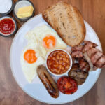 Traditional London food: overhead shot of white plate with a full English breakfast.