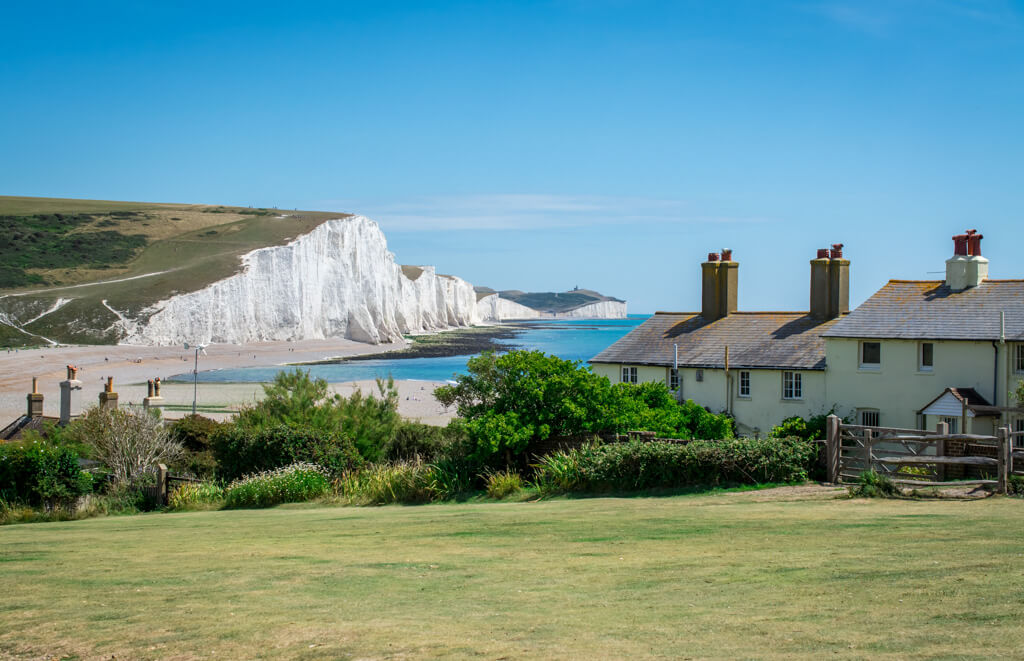 The striking white cliffs of the Seven Sisters overlooking the English channel with cottages in the foreground. 