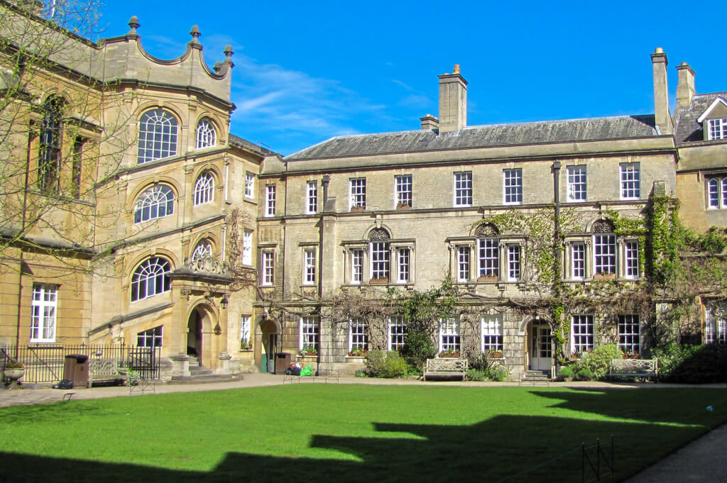 Golden stone courtyard in Oxford college with enclosed spiral stairway and lawn. Copyright@2025 NancyRoberts