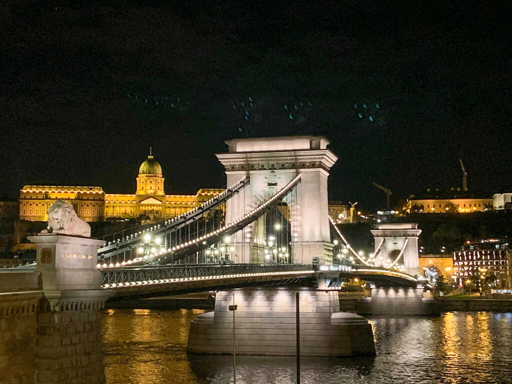 Budapest Chain bridge and historic buildings in background illuminated at night and reflecting in river Danube. Copyright@2025reserved to photographer via MapandFamily