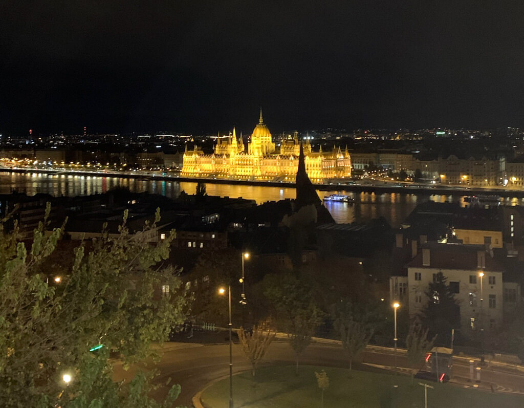 View of golden Parliament buiding lit up at night from Buda Castle. Copyright@2025reservedto phtographer via Mapandfamily.com
