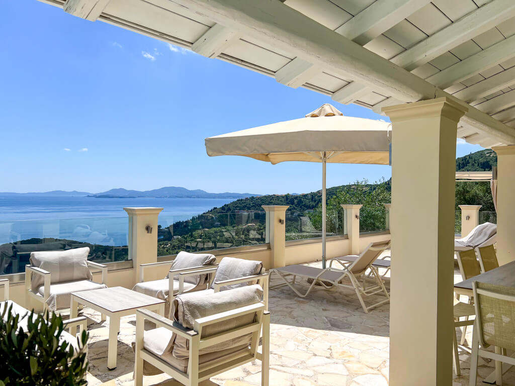 Villa Bliss Kalami Corfu view of terrace with outdoor furniture and sun umbrella in shades of cream and beige. Copyright@2025NancyRoberts